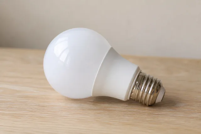 Ampoule LED blanche à culot E27 sur une table en bois, illustration créée pour 99outils.